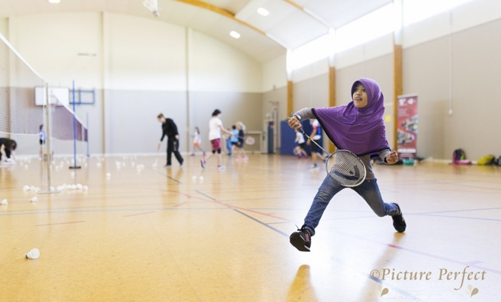 Muslim girl playing badminton in a gym 