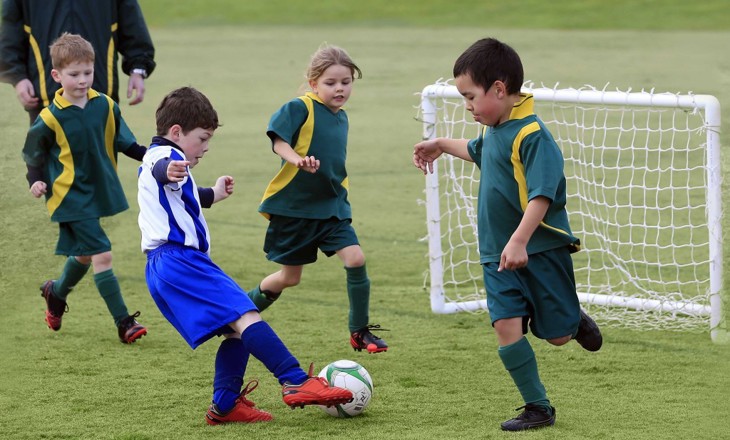 Young kids playing football on a field 