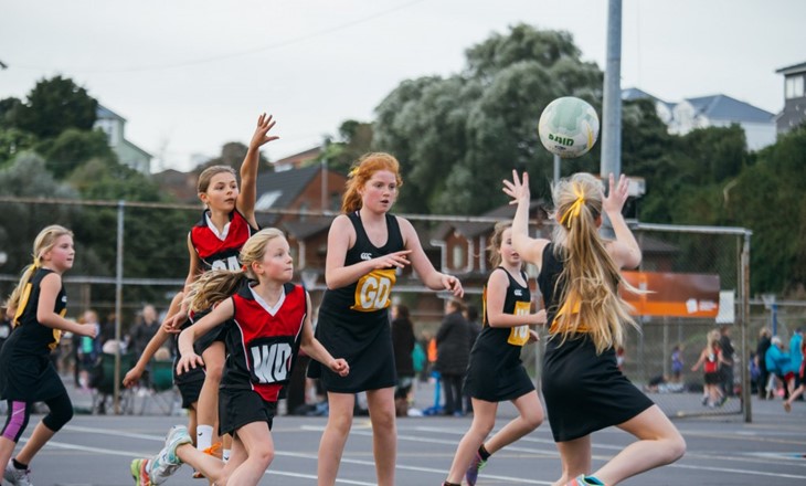A group of girls playing a netball game on a court