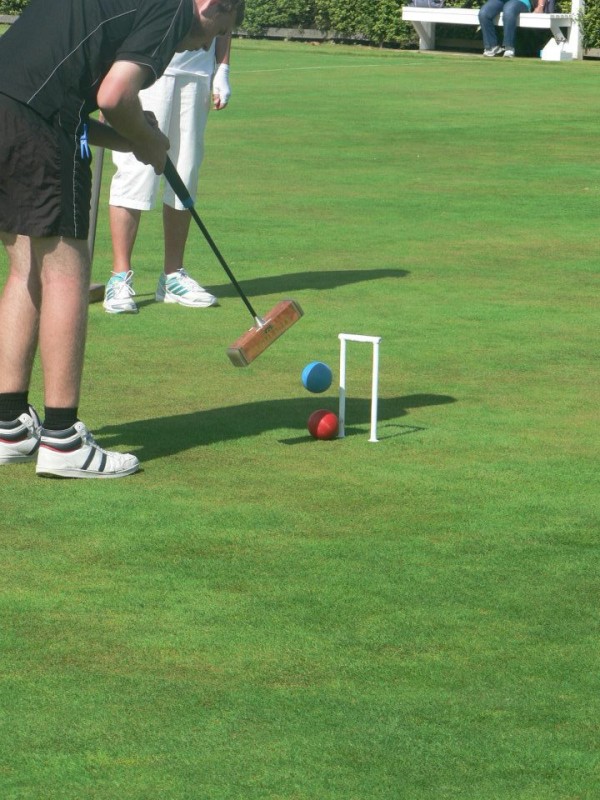 Croquet player making their shot through the hoop