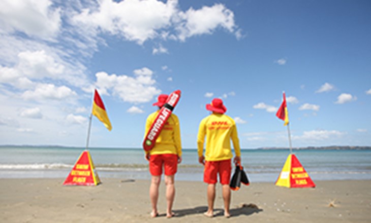 Lifeguards stand between the flags looking seaward