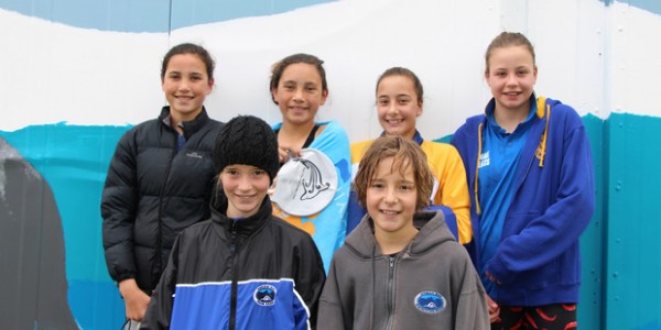 5 kids standing against a wall at a swim meet