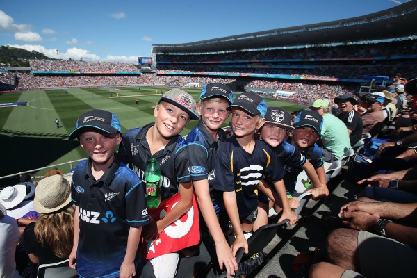6 young cricket fans at a stadium looking to the camera