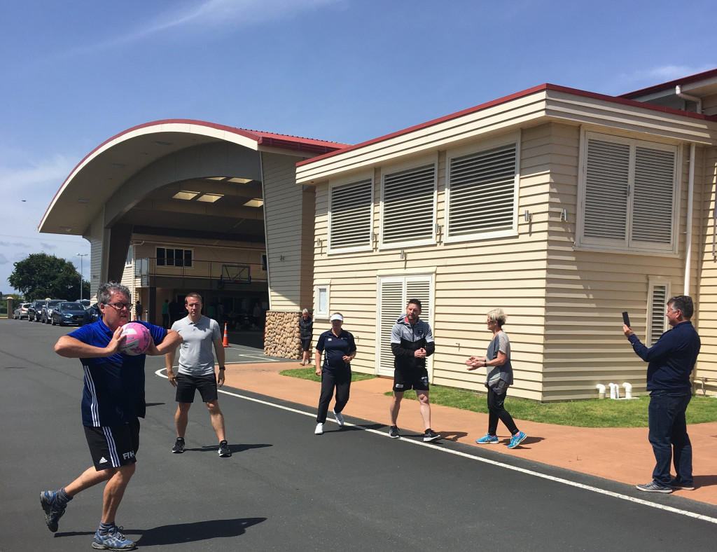 Group of adults playing with a ball outside on tarmac