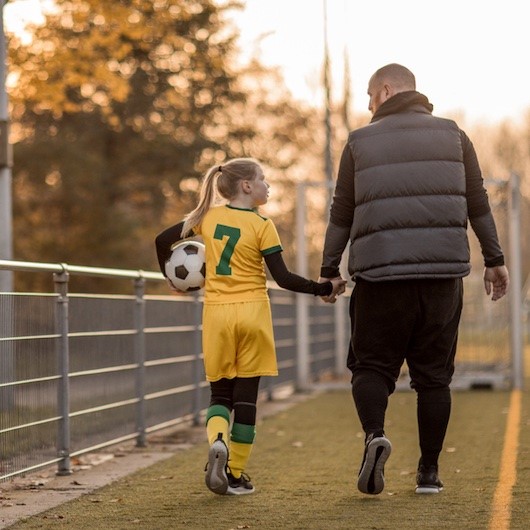 Parent holding their daughters hand after a soccer match