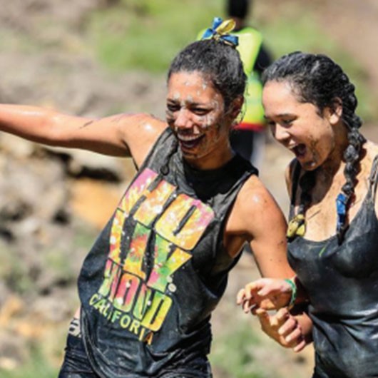Two girls partaking in a muddy challenge