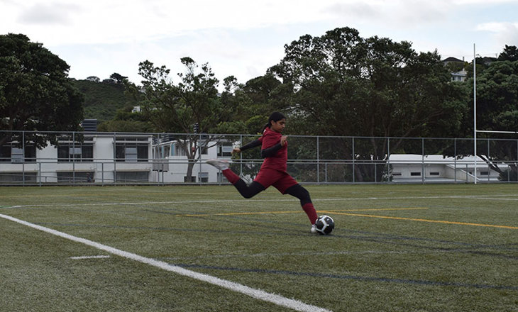 Girl kicking a football on a field 