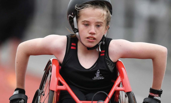 Girl pushing a racing wheelchair down the track