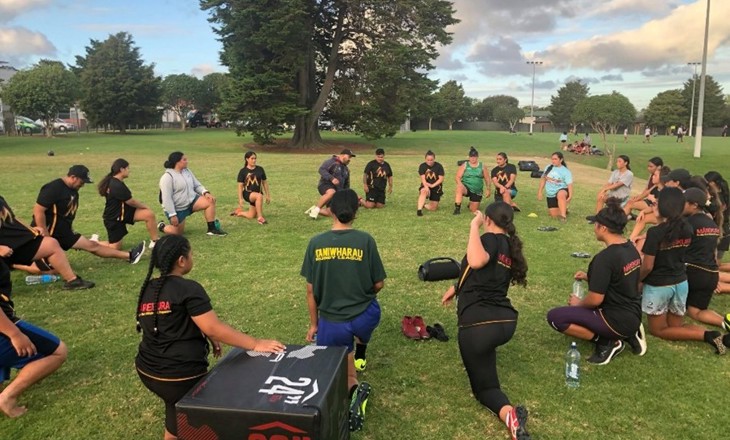 People stretching in a circle at a park