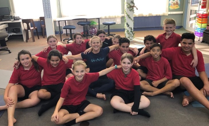 Kids sitting on a classroom floor looking to camera