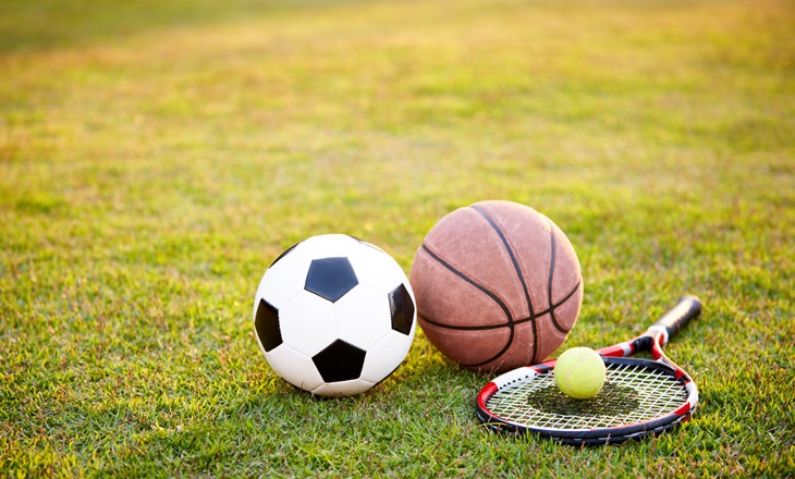 Football soccer ball basketball tennis ball and racket laid 