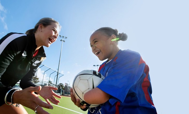 Girl smiling and playing with a rugby ball