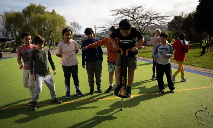 Child on a pogo stick surrounded by friends