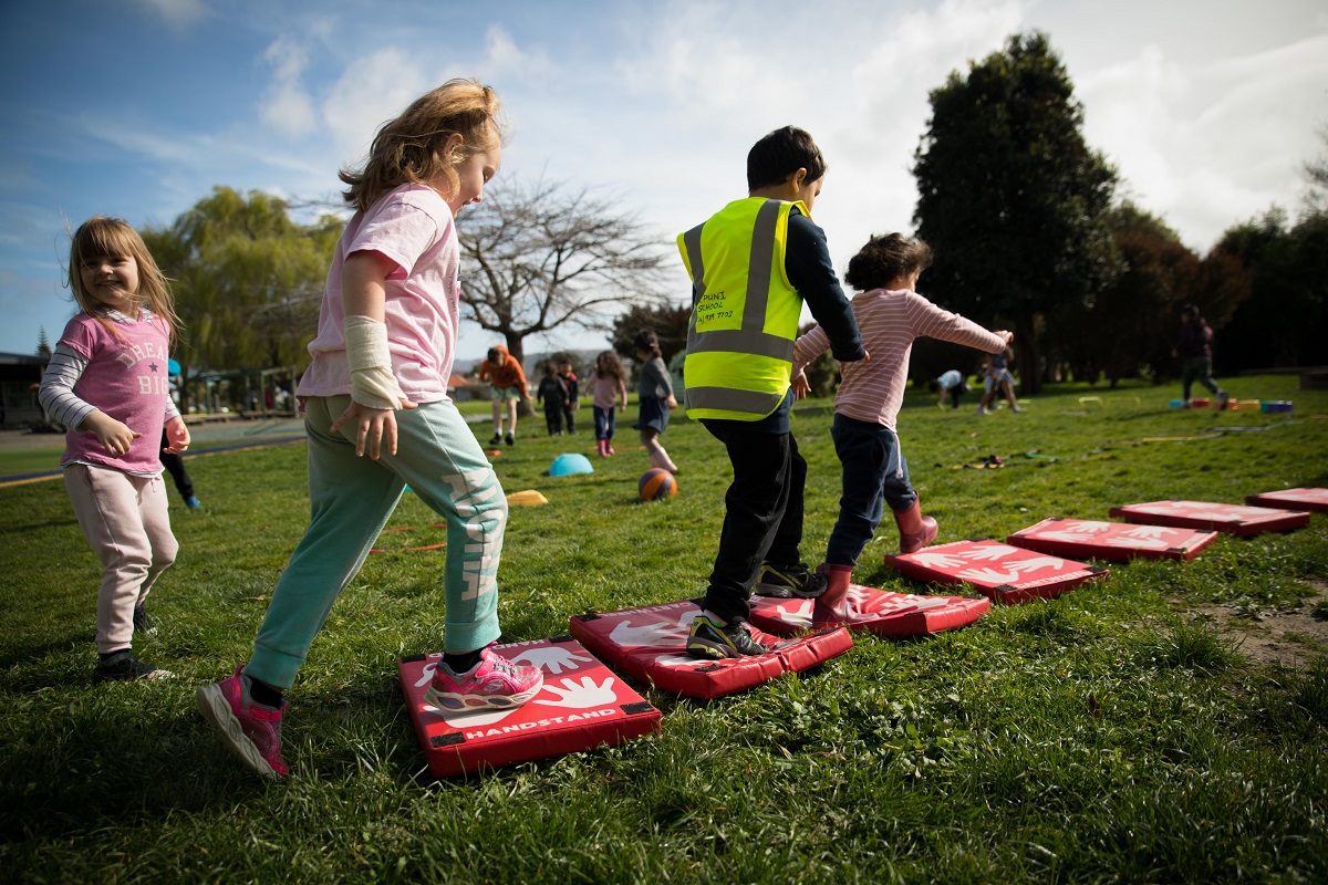 Kids jumping over soft platforms on grass