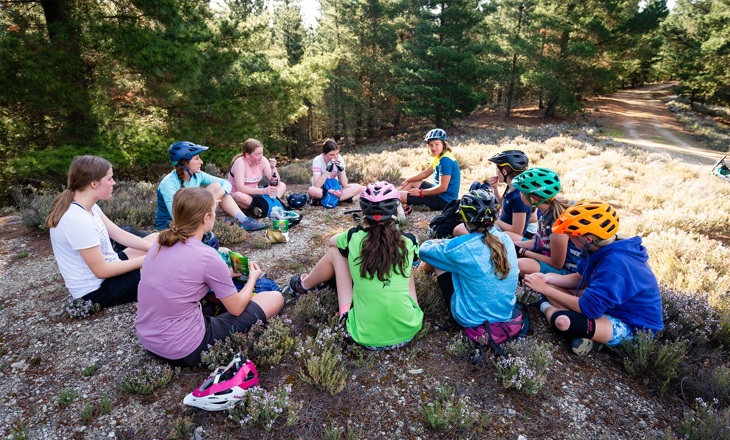 Group of rangatahi sitting in a circle with helmets on