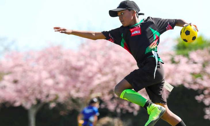 Boy jumping with ball during game of ki o rahi