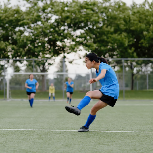 Young woman kicking ball at football game