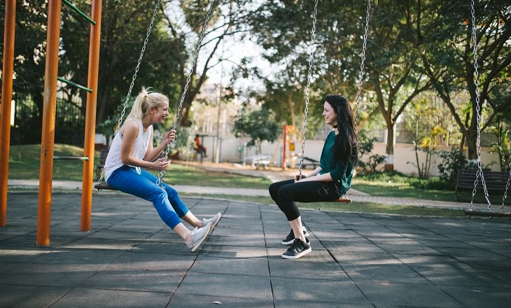 Two young women on swings facing each other