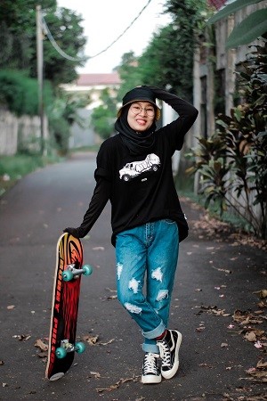 Rangatahi woman holding a skateboard on walkway