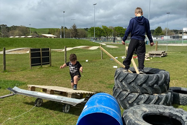Two kids climbing over tyres and wooden pallets