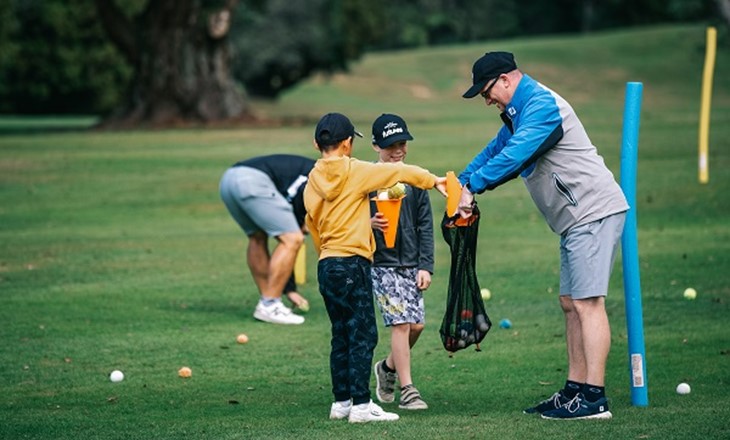 Two boys on a golf course with their coach