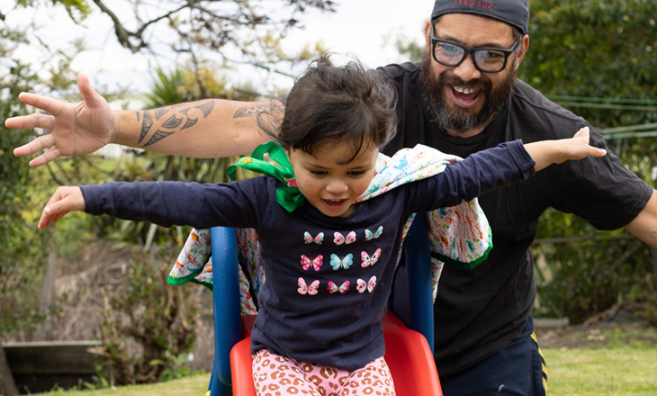 Father and daughter enjoy pretending to fly on a slide