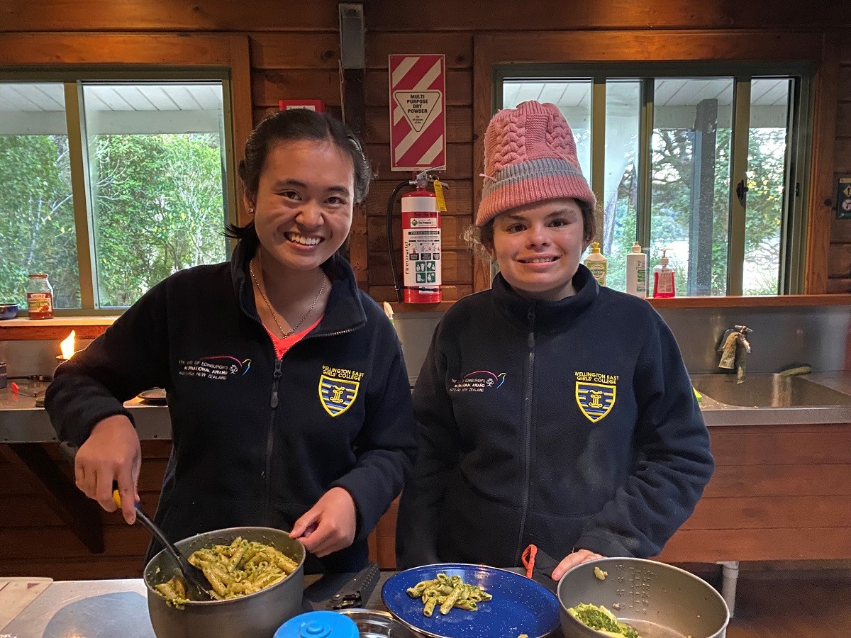 Two students cooking a meal of pasta in a kitchen