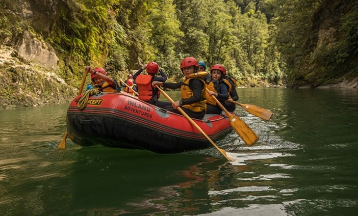 Group of young people rafting through a river