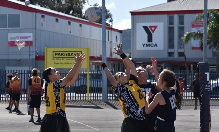 Young women playing netball on a court