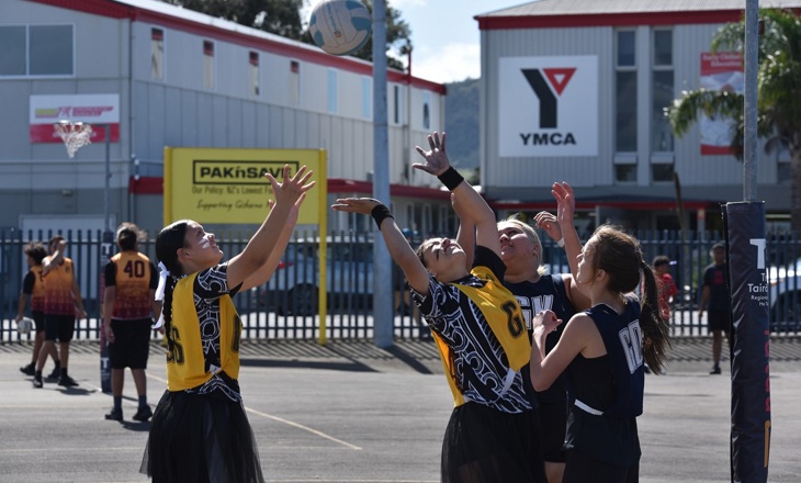 Young women playing netball on a court