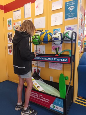 Tamariki choosing an item from the Play shelf at the library