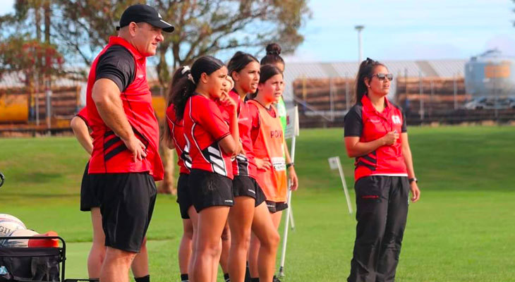 Coach and team watch a game from the sidelines