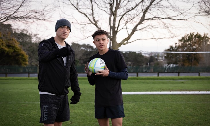 Father and son on a field holding a soccerball