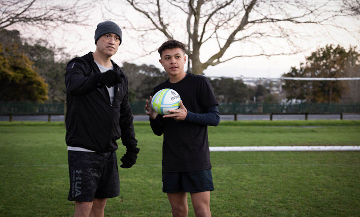 Father and son on a field holding a soccerball