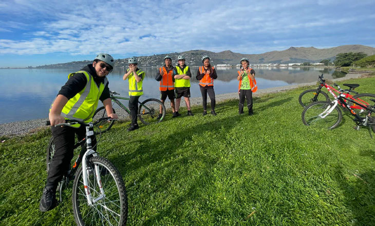A group of cyclists at a lakes edge.