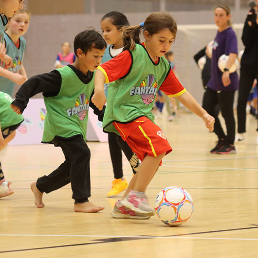 Kids playing football in a hall for pe image