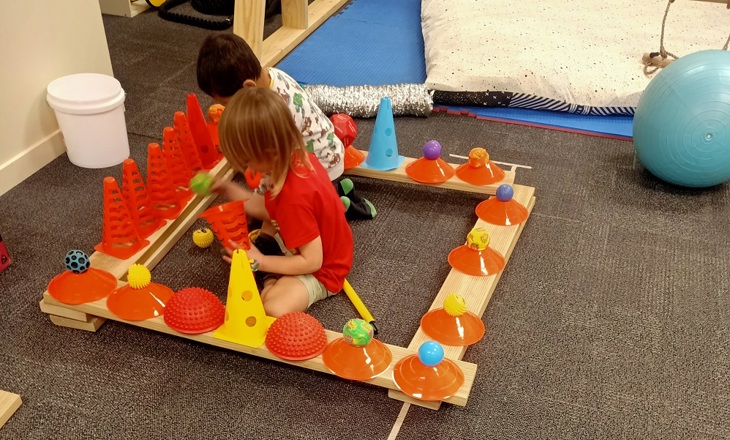 two children playing with spare parts in a wooded structure