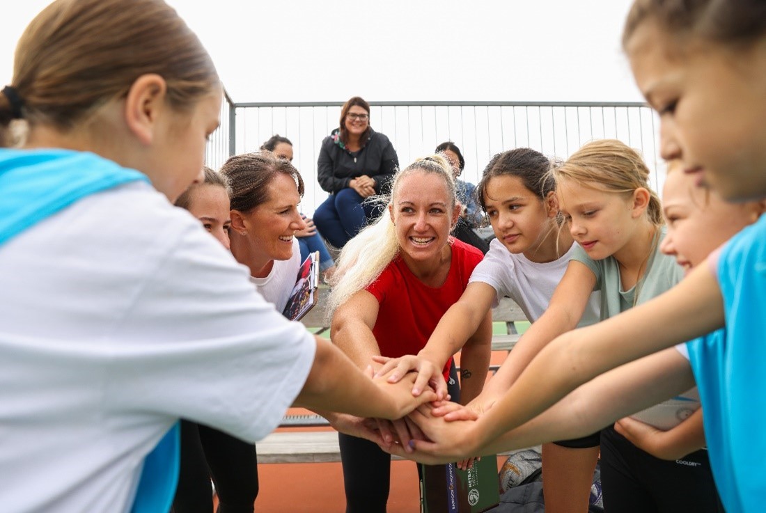 Young women with their hands together before a netball game