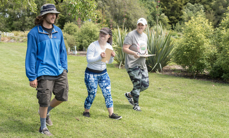 Three people walking in the park with clipboards