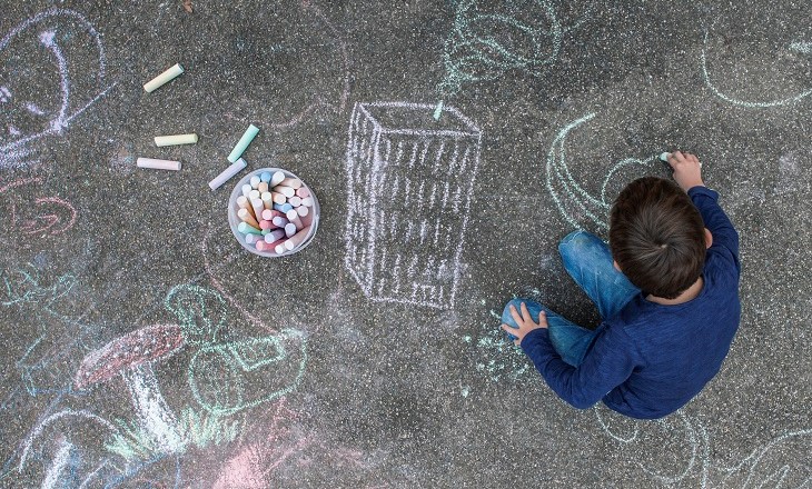 Tamariki/child drawing on a pavement with chalk