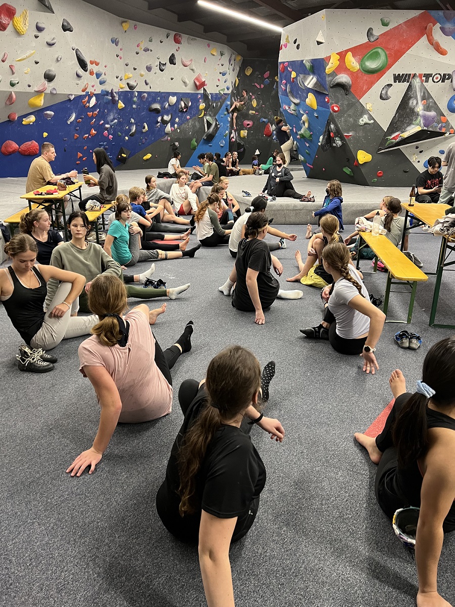 Rangatahi stretching on the floor of a climbing gym