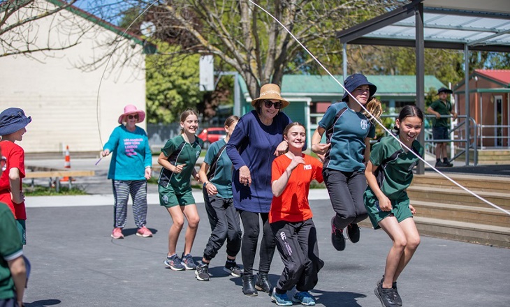 Group of students and their teacher doing long skipping rope