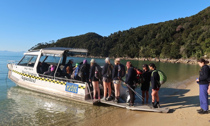 Young people boarding a boat from a beach