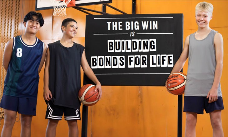 3 boys on basketball court in front of blackboard