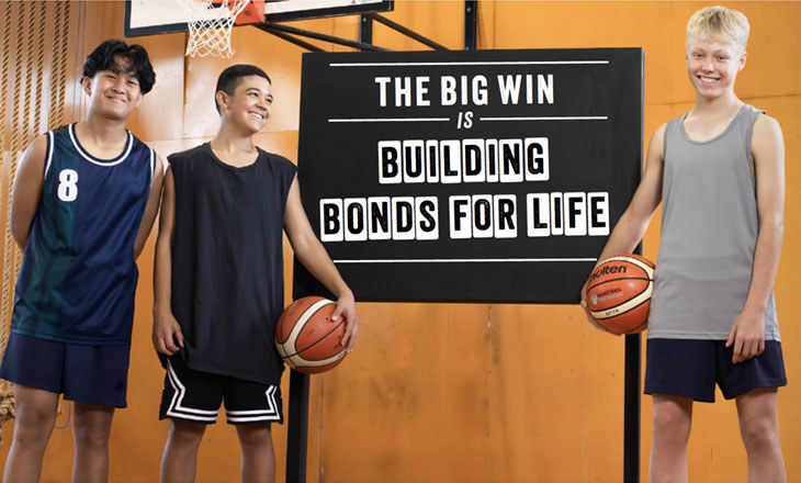 3 boys on basketball court in front of blackboard