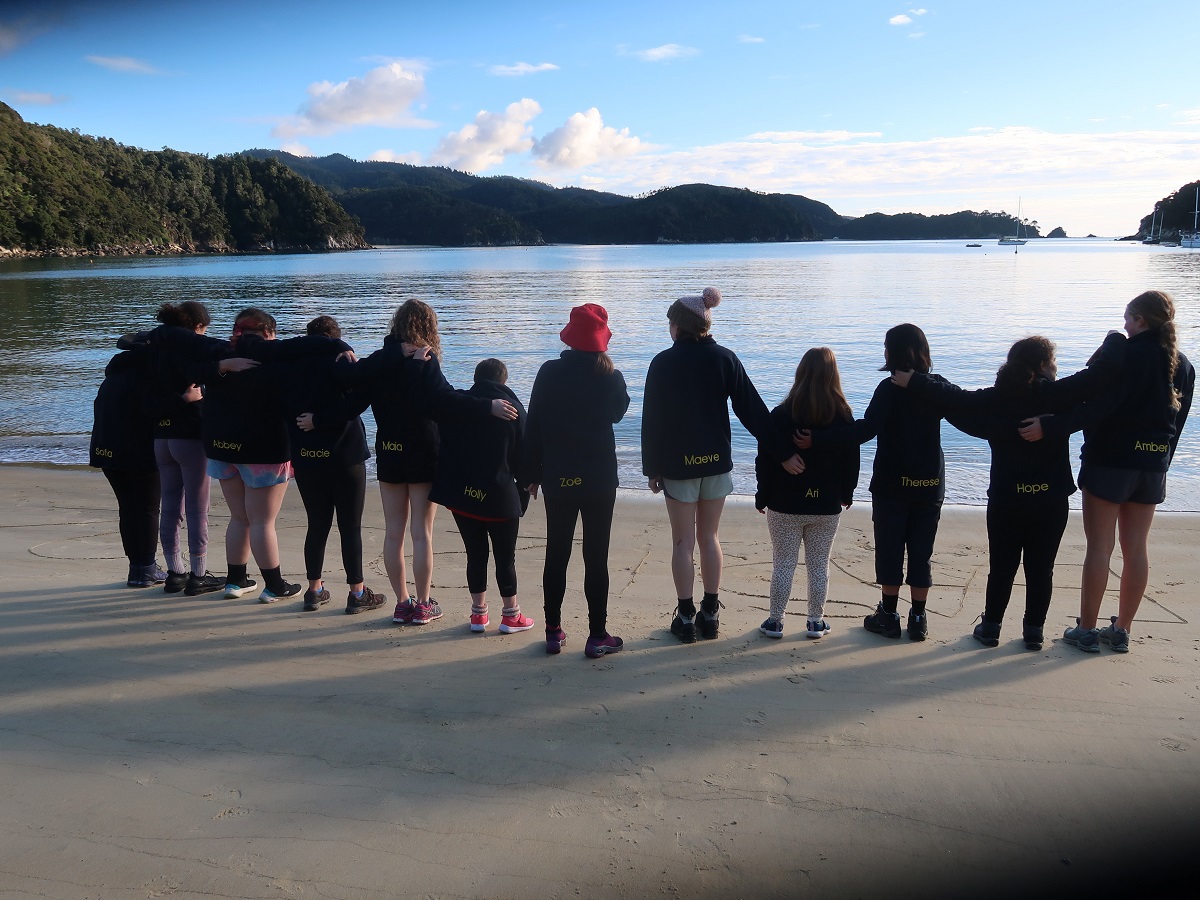 Group of students standing in a semicircle on a beach