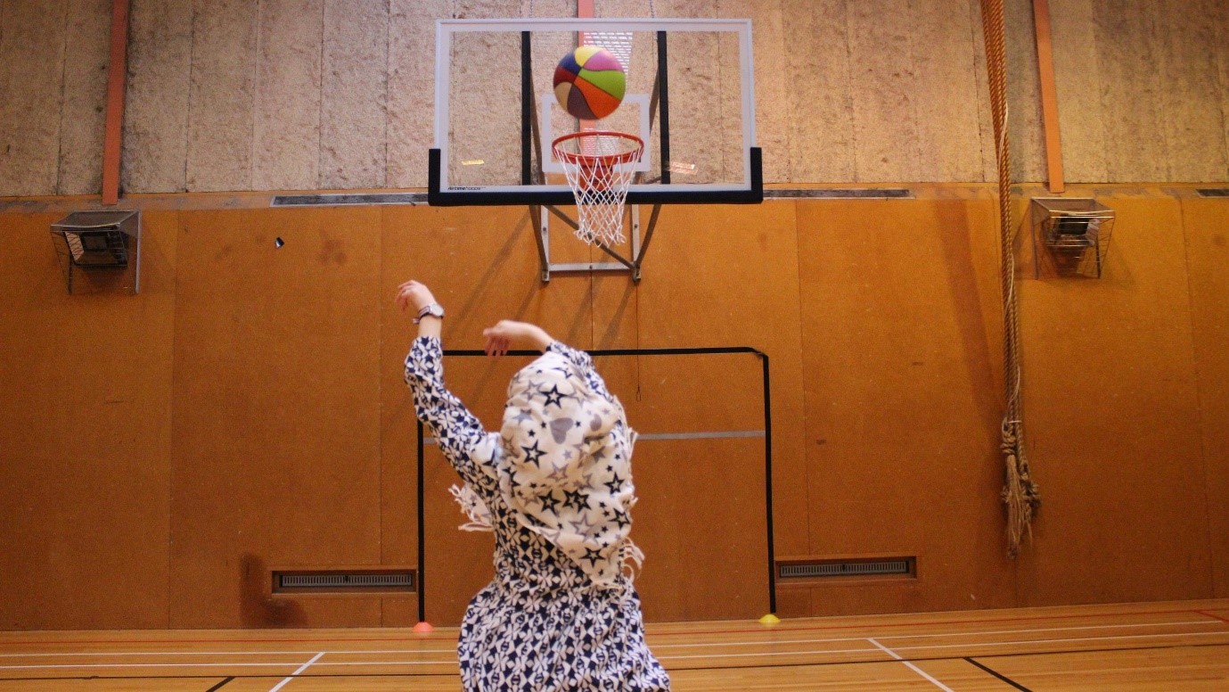 Young woman throwing a ball into a hoop in a gym
