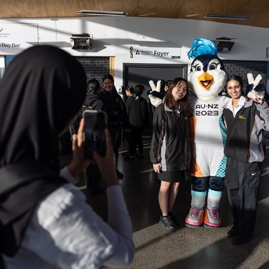 Two young women standing with the Fifa mascot