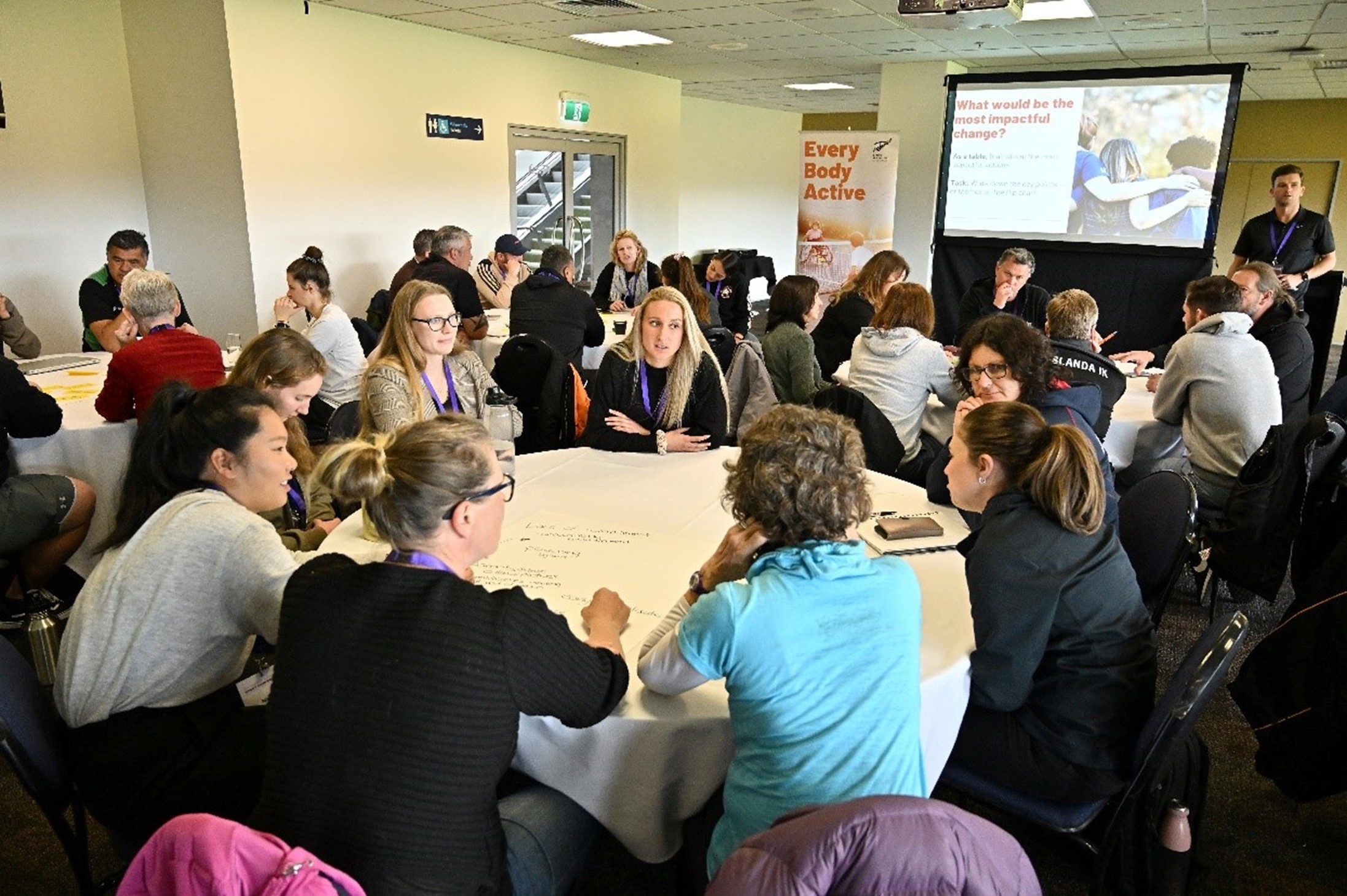 People sitting at round tables at a hui