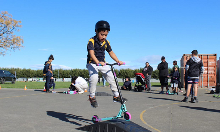 Child hopping over a ramp with a scooter